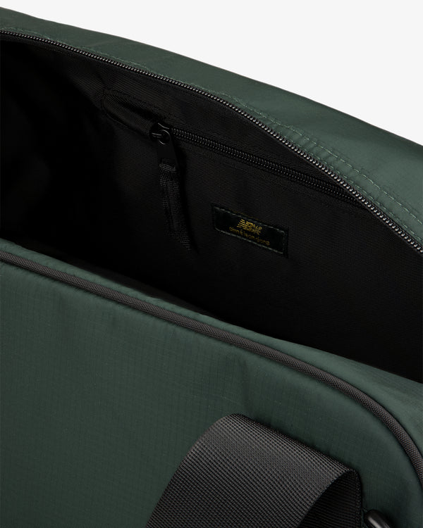 Close-up of the open ALD / New Balance Travel Duffle Bag showing a zippered pocket and black strap inside.