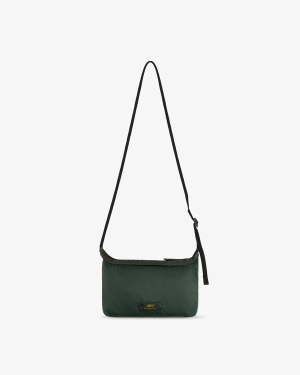 ALD / New Balance Nylon Sling Pouch in dark green with black adjustable strap on a white background.