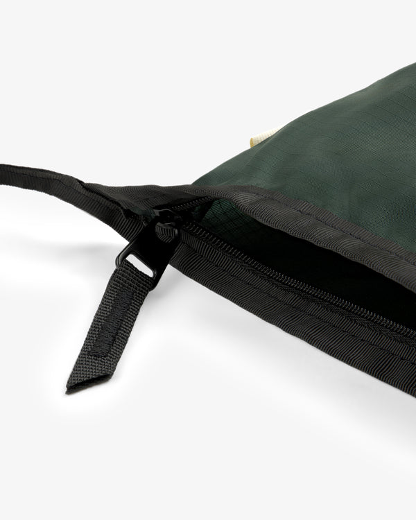 Close-up of the ALD / New Balance Nylon Sling Pouch in green with black zipper and strap on a white background.