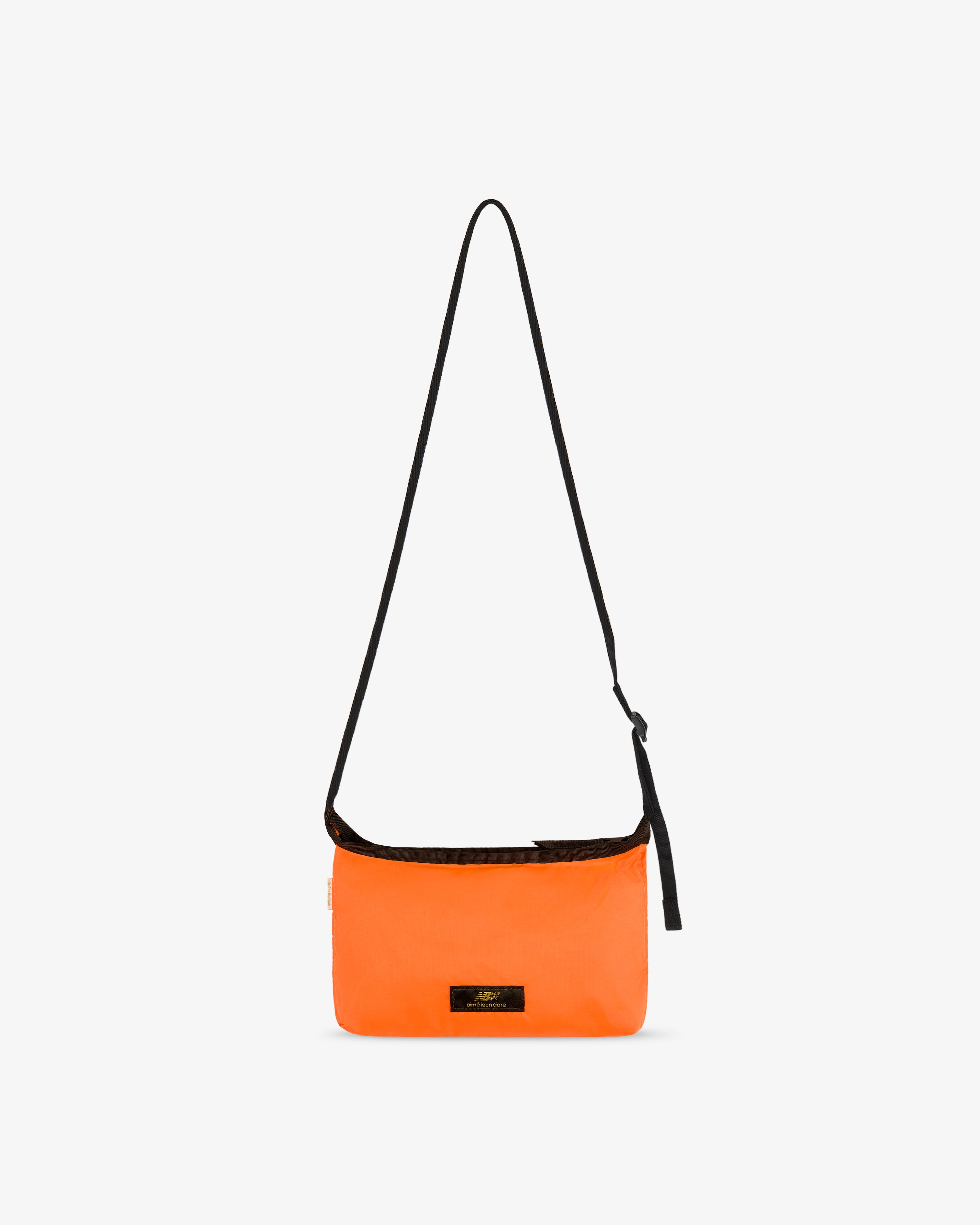 ALD / New Balance Nylon Sling Pouch in bright orange with long black strap and small black front label on white background.