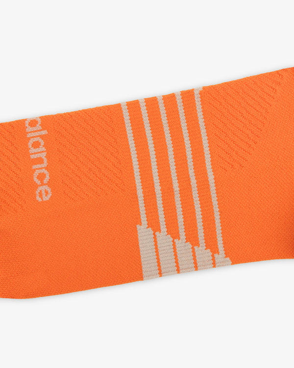 ALD / New Balance Running Crew Sock: orange with white diagonal stripes and partial white text on left side.