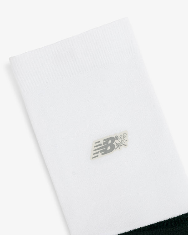 ALD / New Balance Running Crew Sock featuring a gray logo and small flower graphic near the top on white.