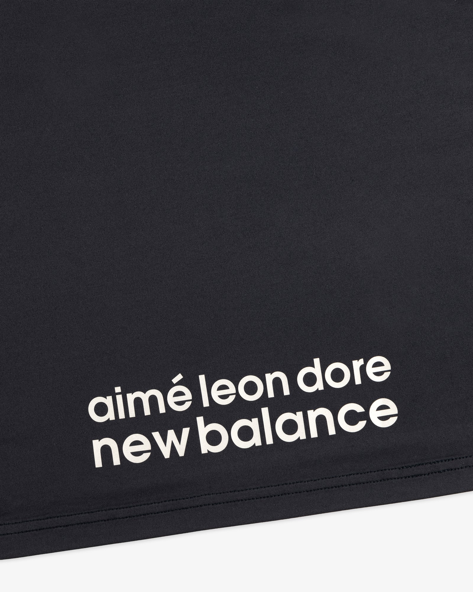 Close-up of black fabric from the ALD / New Balance Performance Long-Sleeve Tee with white printed lettering.