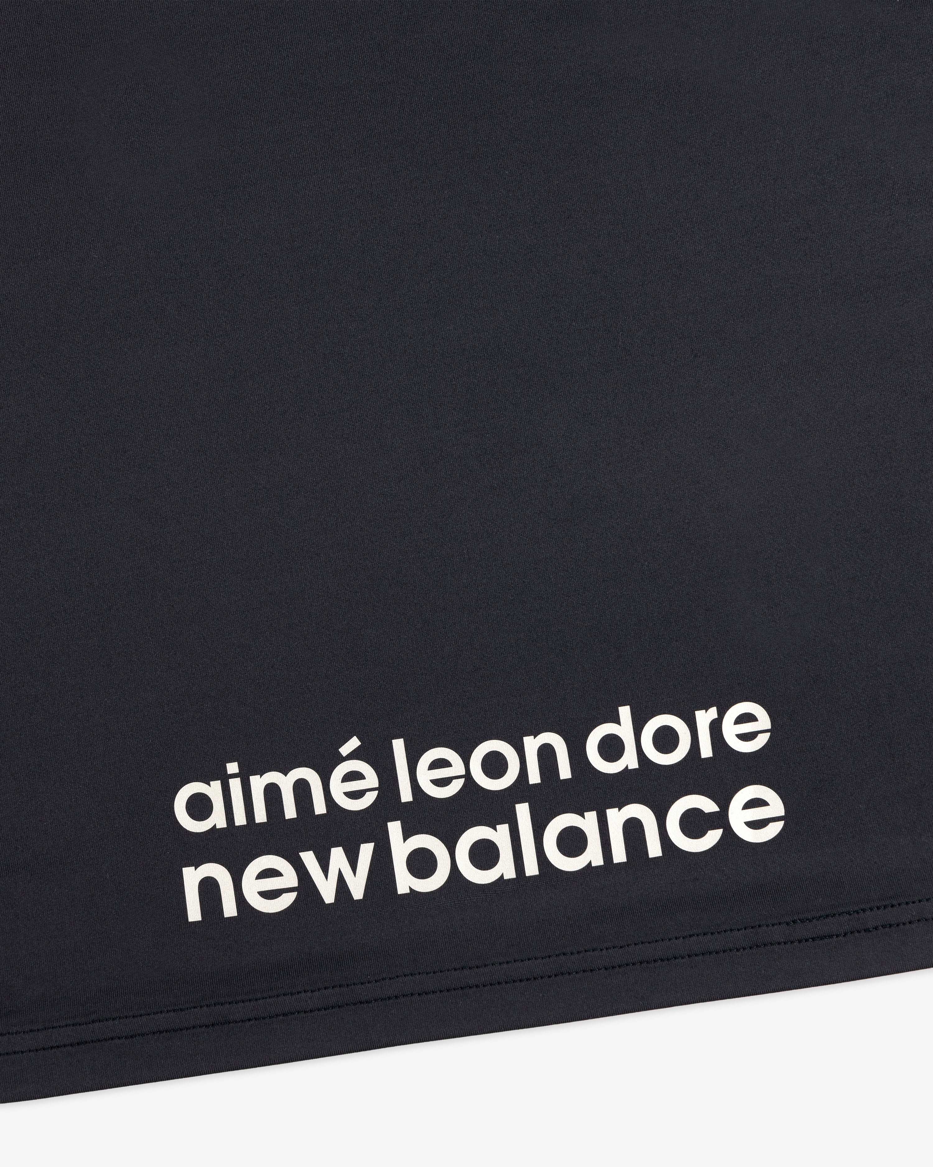 Close-up of black fabric from the ALD / New Balance Performance Long-Sleeve Tee with white printed lettering.