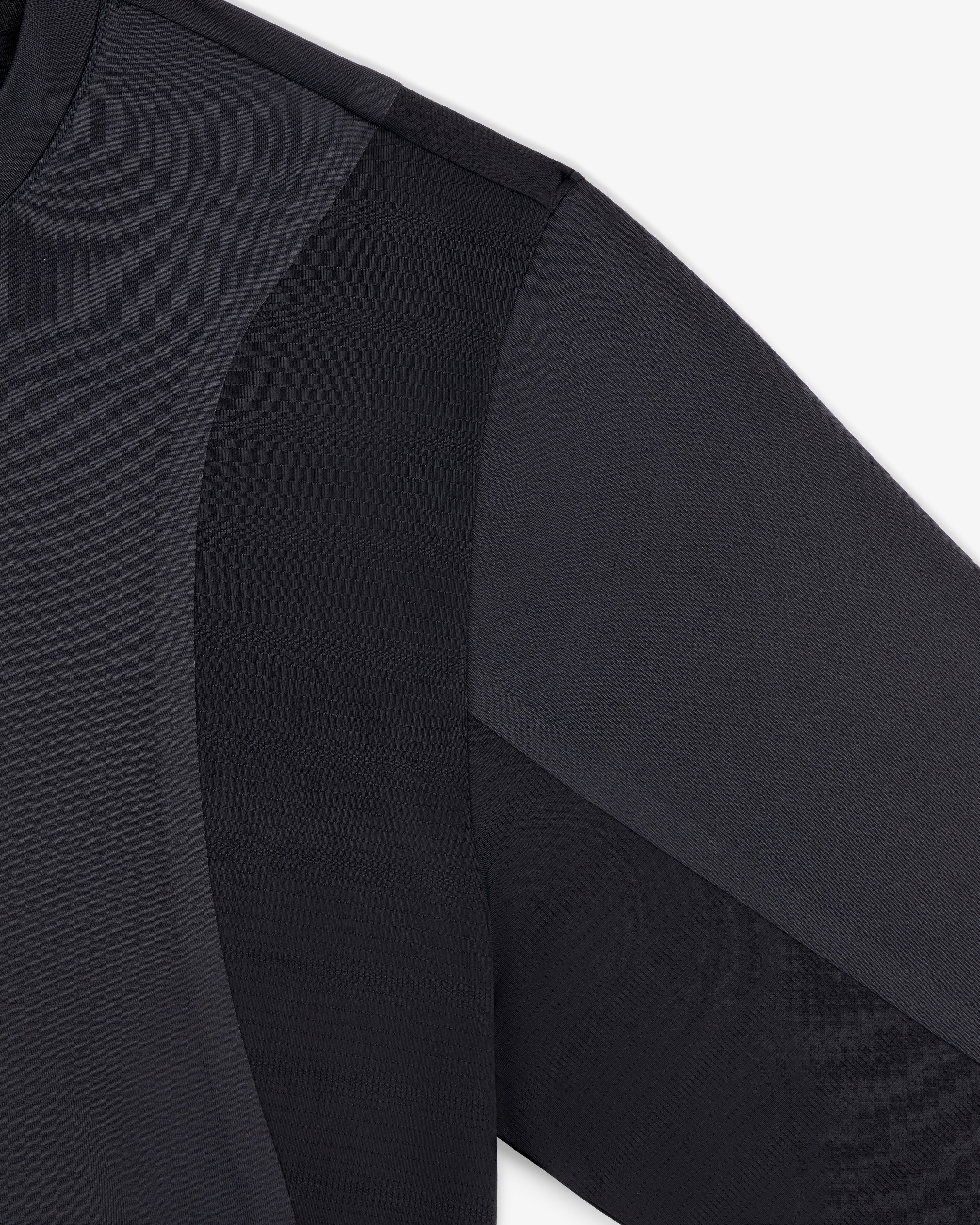 Close-up of the ALD / New Balance Performance Long-Sleeve Tee shows black fabric texture and seam details on shoulder and arm.