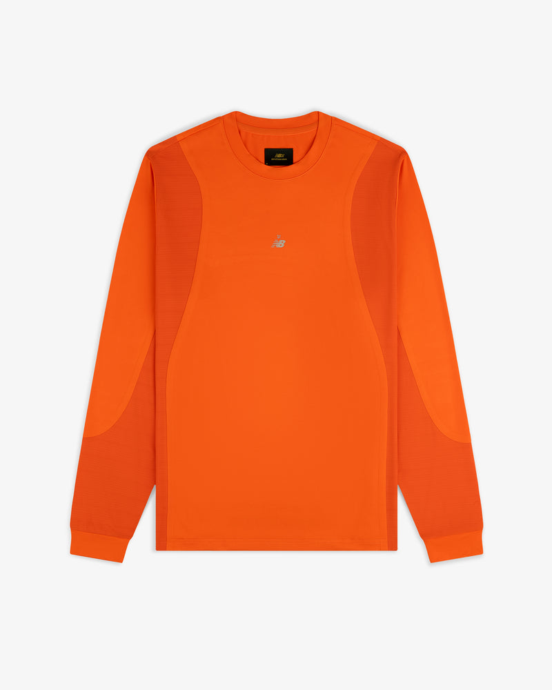 ALD / New Balance orange performance long-sleeve tee with panel details and small white chest logo, laid flat on white.