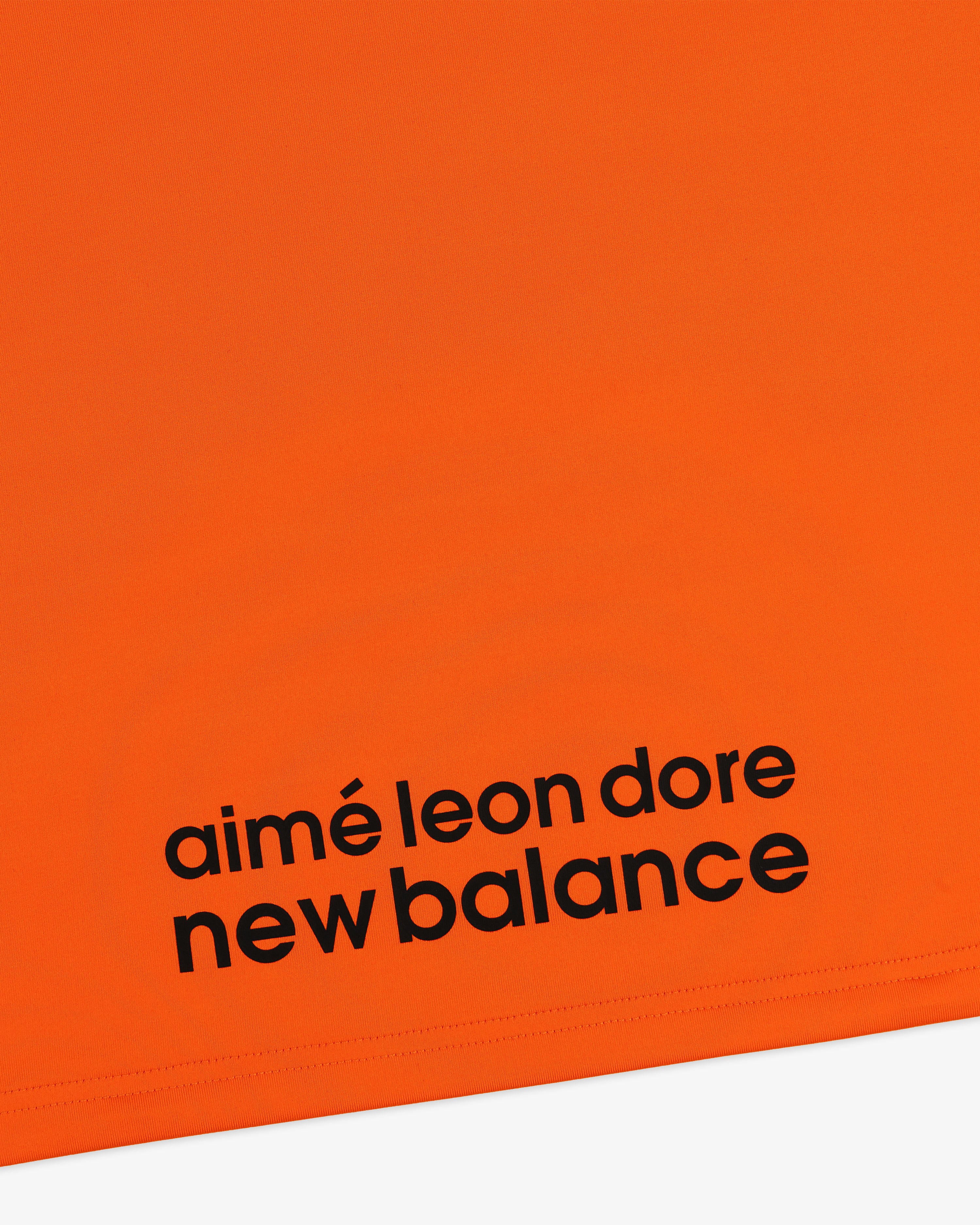 Bright orange ALD / New Balance Performance Long-Sleeve Tee with bold black branding near the bottom edge.