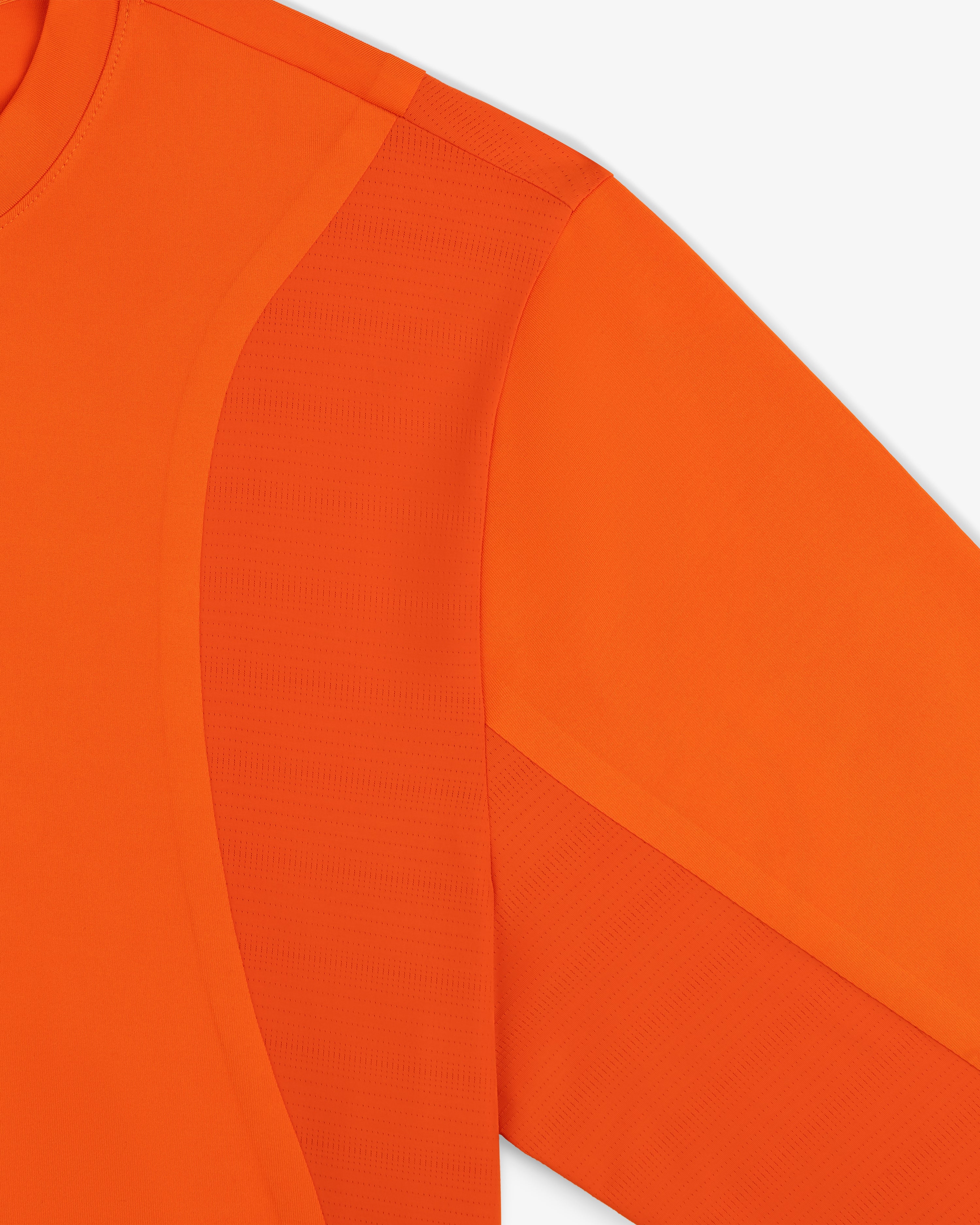 A close-up of the ALD / New Balance Performance Long-Sleeve Tee in orange with textured and smooth panels.