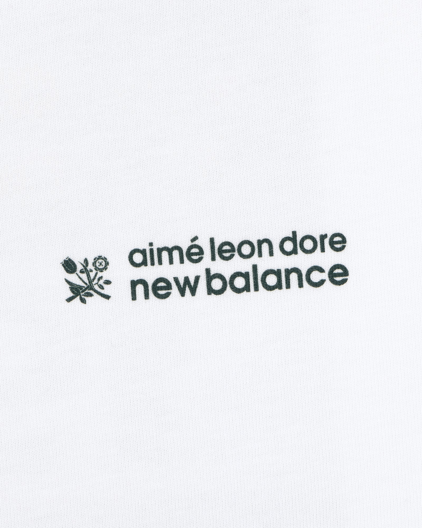 ALD / New Balance Running Bib Tee with black text and floral graphic on white fabric background.