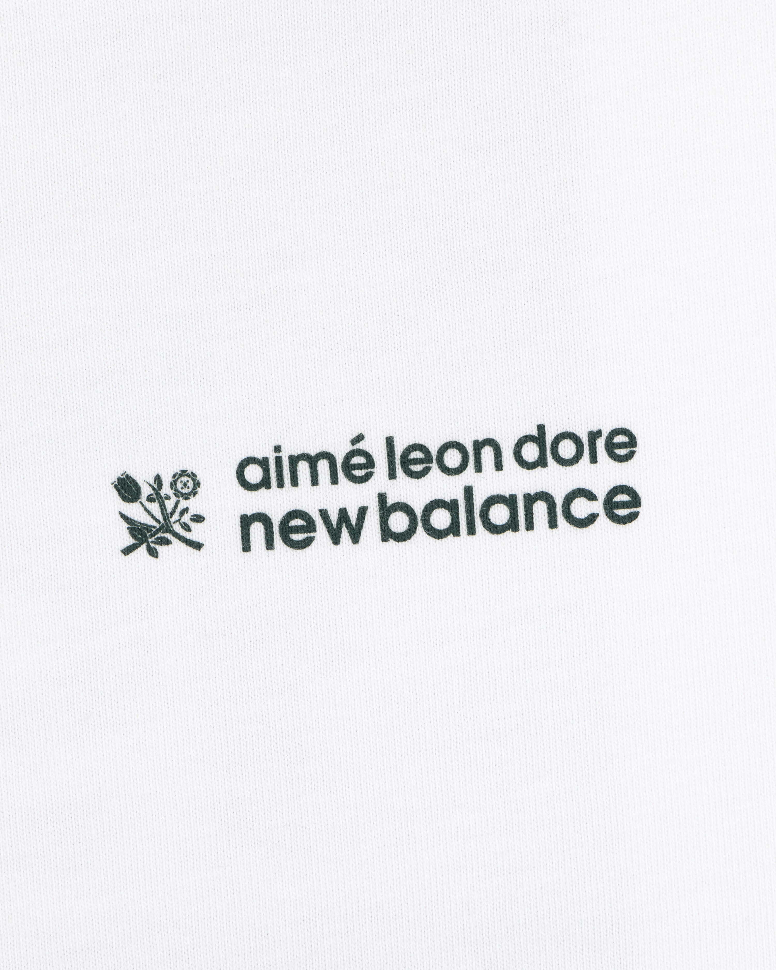 ALD / New Balance Running Bib Tee with black text and floral graphic on white fabric background.