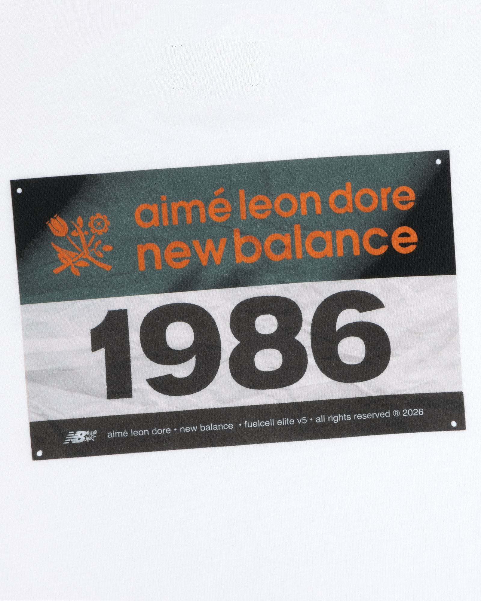 The ALD / New Balance Running Bib Tee features a race bib with 1986, shown on a white background.