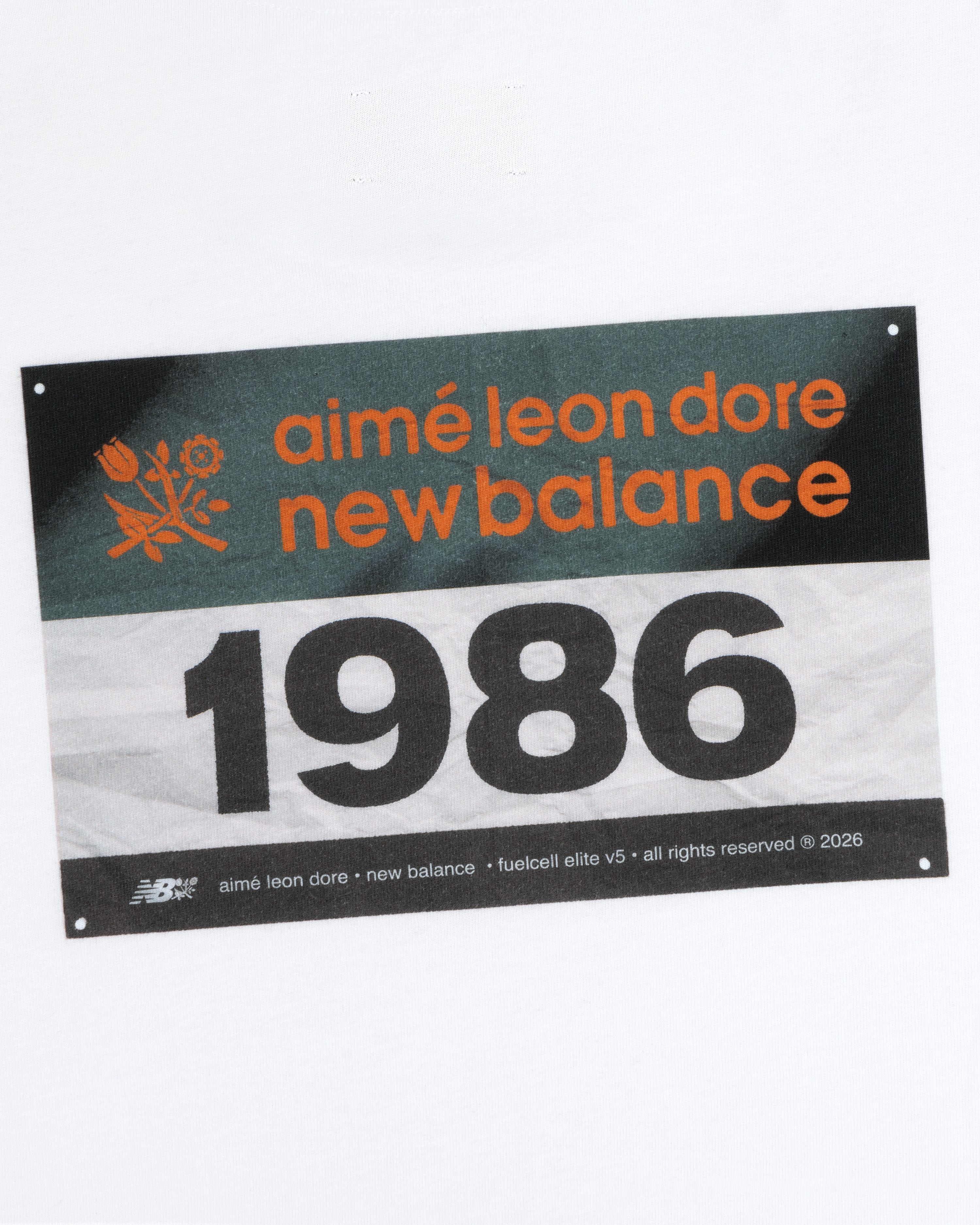 The ALD / New Balance Running Bib Tee features a race bib with 1986, shown on a white background.