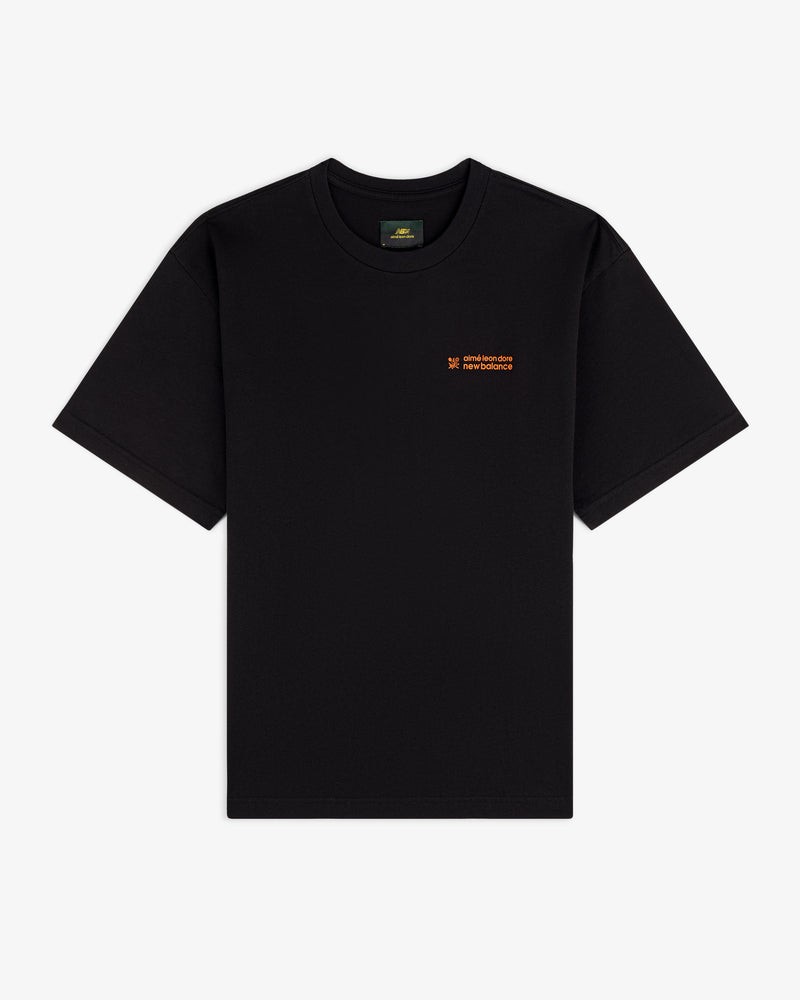 ALD / New Balance Running Bib Tee, black short-sleeve with small orange text on left chest, flat on white background.