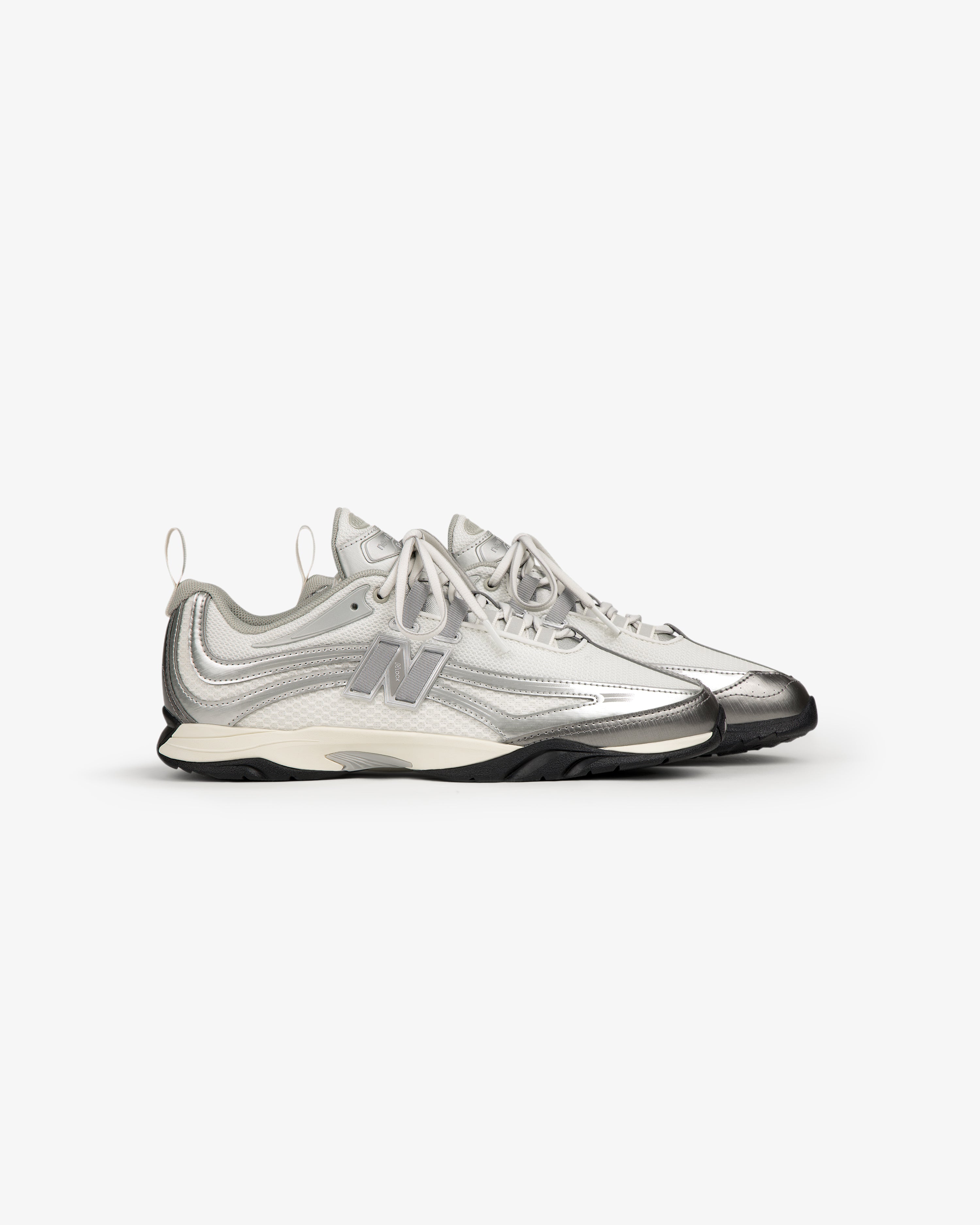 ALD / New Balance RC56: Silver and white athletic sneakers with laces, side logo, and black soles.