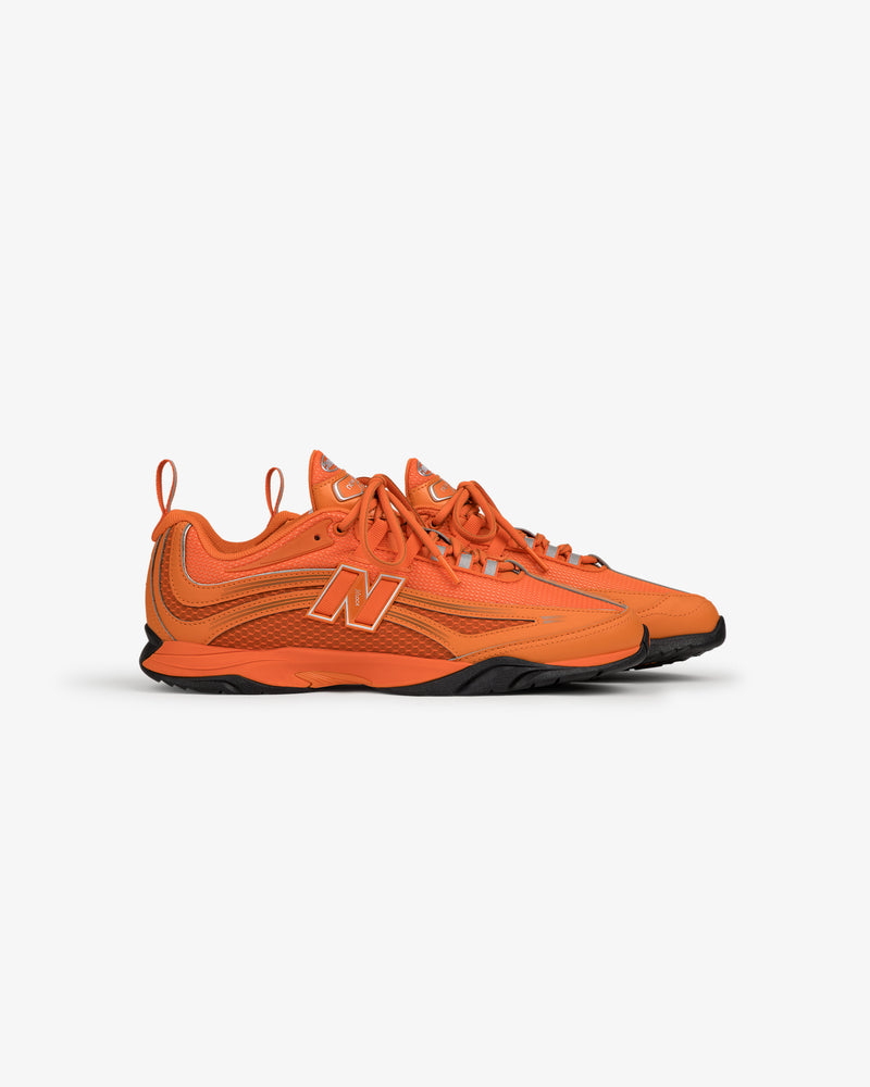 ALD / New Balance RC56 bright orange sneakers with black soles, side view, on plain white background.