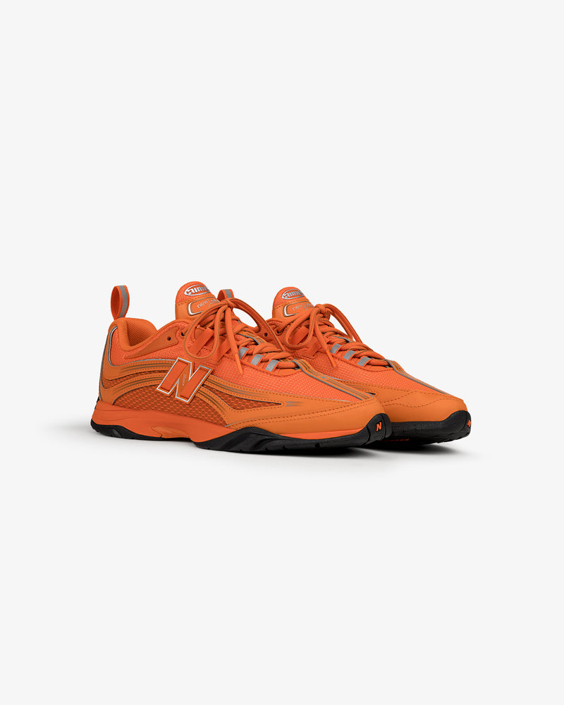 A pair of bright orange ALD / New Balance RC56 sneakers with black soles, side logo, and orange laces on white.