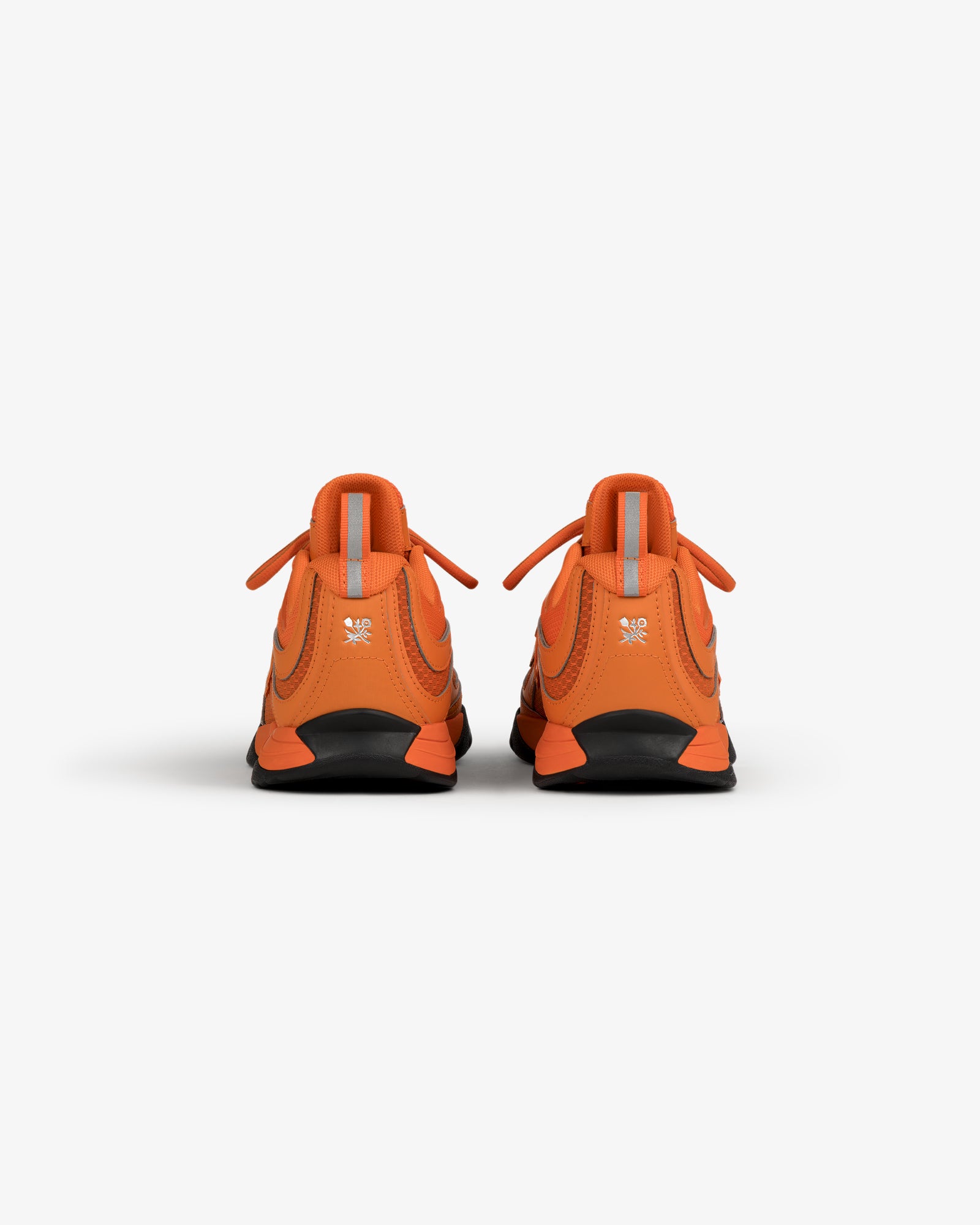 Back view of ALD / New Balance RC56 orange sneakers with reflective gray tabs and black soles on a white background.