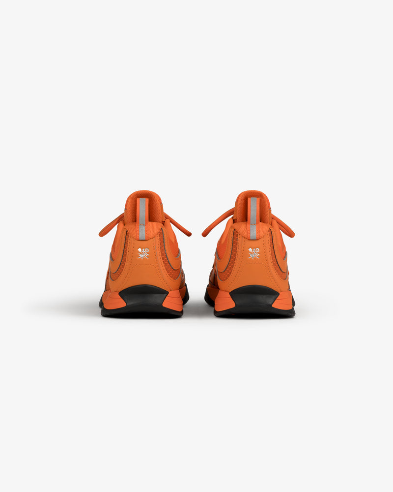 Back view of ALD / New Balance RC56 orange sneakers with reflective gray tabs and black soles on a white background.