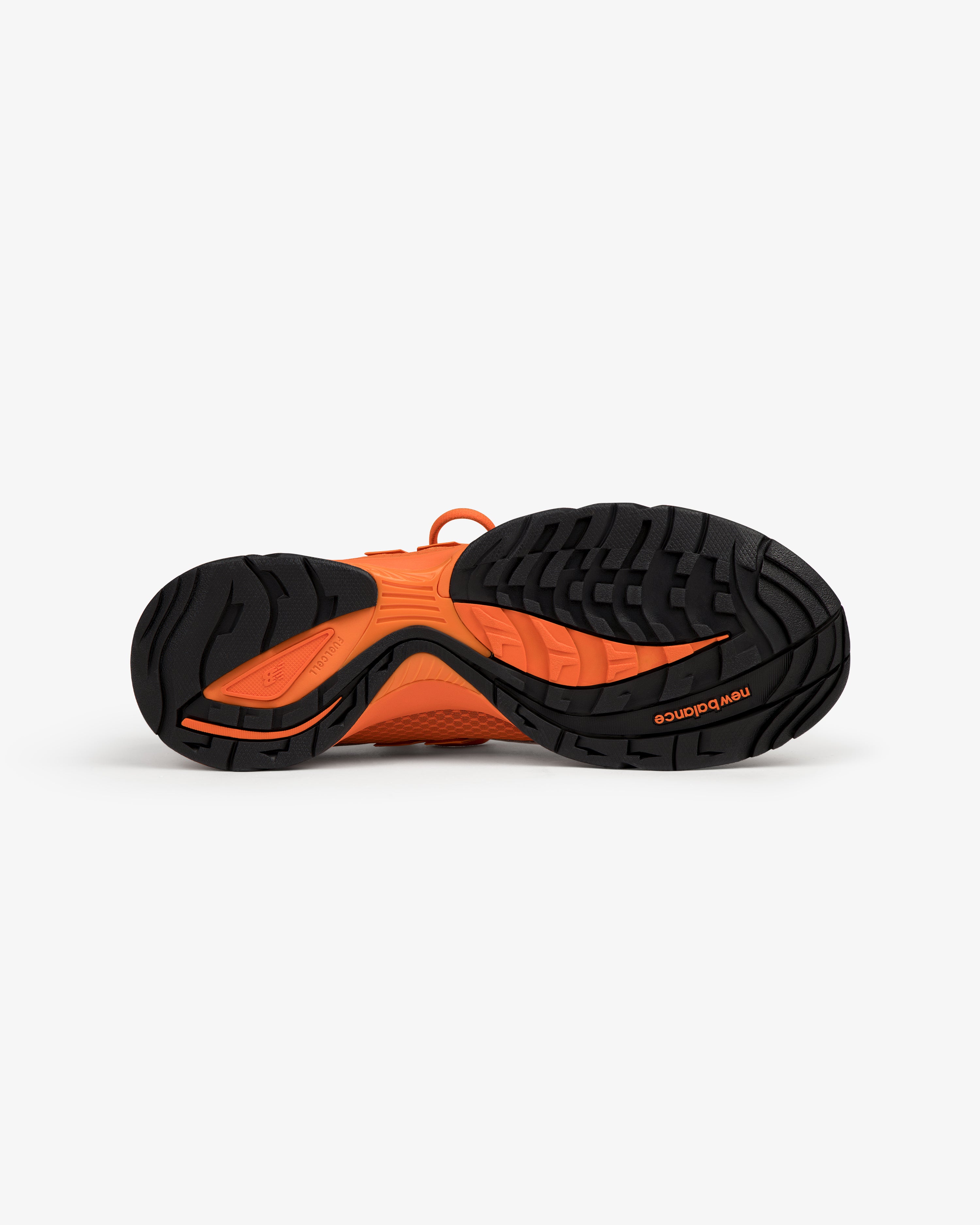 ALD / New Balance RC56 athletic shoe bottom view, showing black and orange tread pattern on a white background.