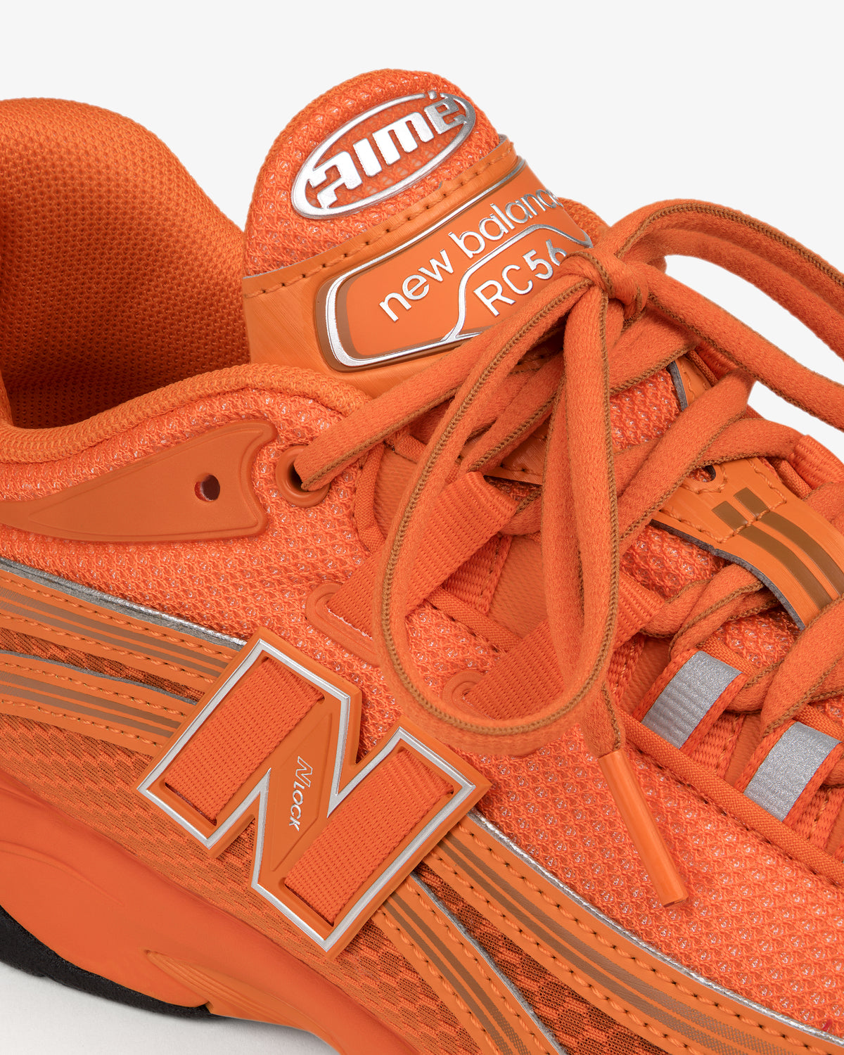 Close-up of an orange ALD / New Balance RC56 sneaker with orange laces and a large “N” logo on the side.