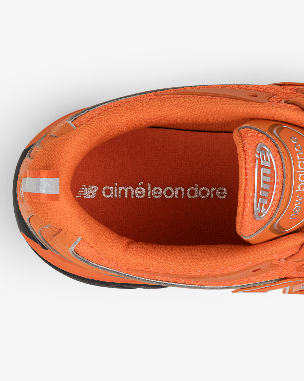 Top view of an orange ALD / New Balance RC56 sneaker with a white logo printed on the insole.