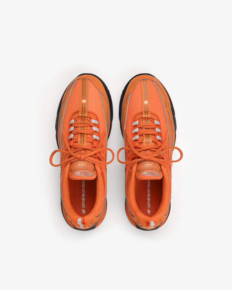 ALD / New Balance RC56 orange athletic sneakers with white accents, top view on a white background.