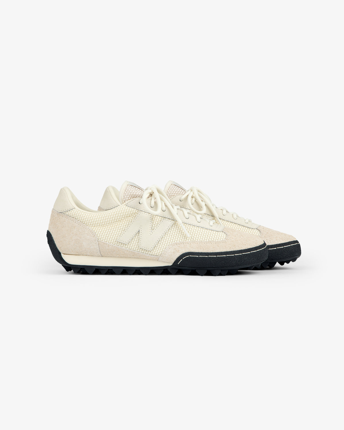 A pair of ALD / New Balance Gator sneakers with off-white textured uppers and black rugged soles on a white background.