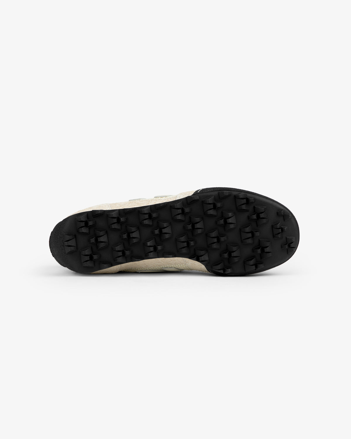 Bottom view of ALD / New Balance Gator beige sneaker with a black, textured rubber sole and raised triangular patterns.
