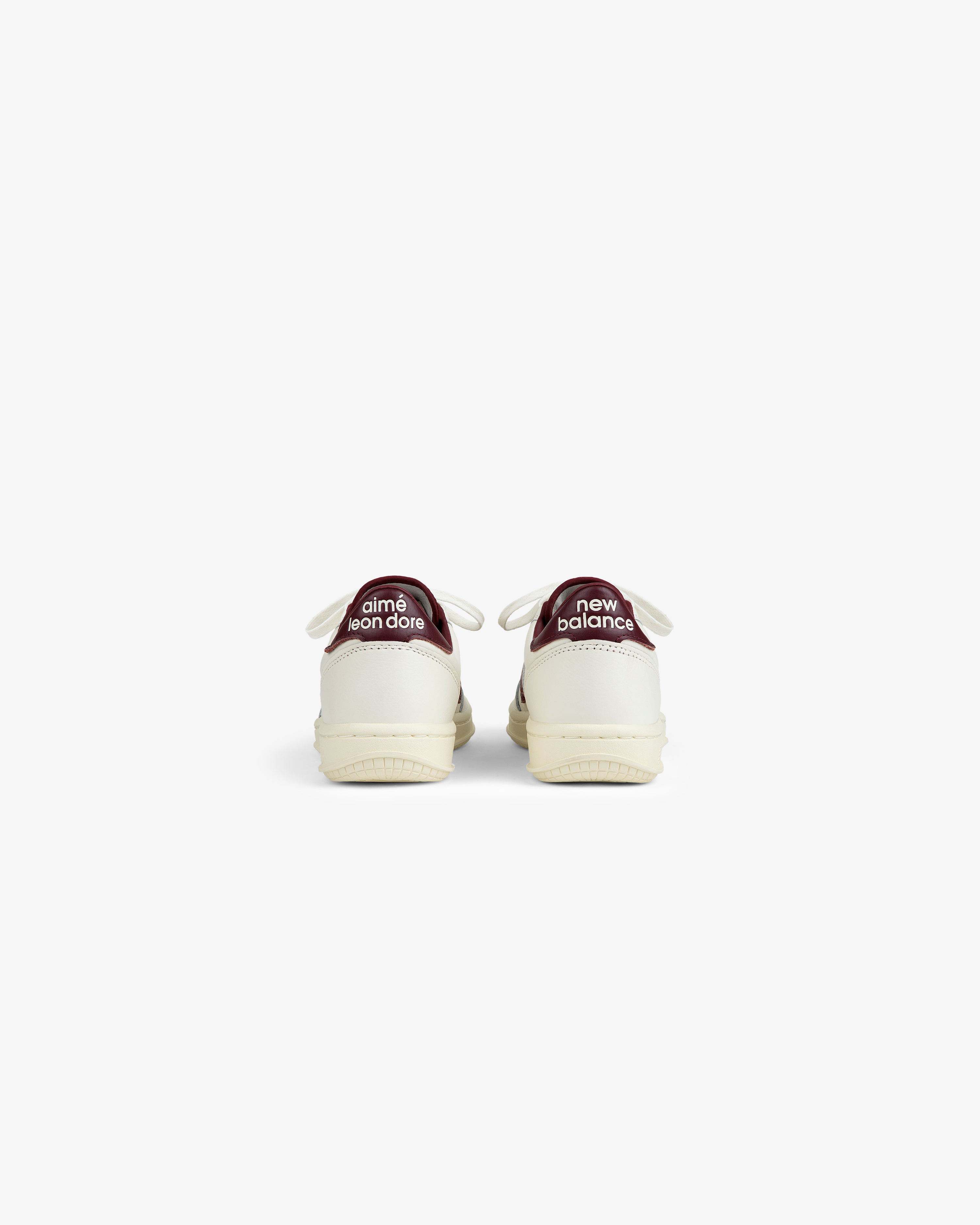 Back view of ALD / New Balance T500 Tennis Oxfords in off-white with dark red heel tabs featuring white text.