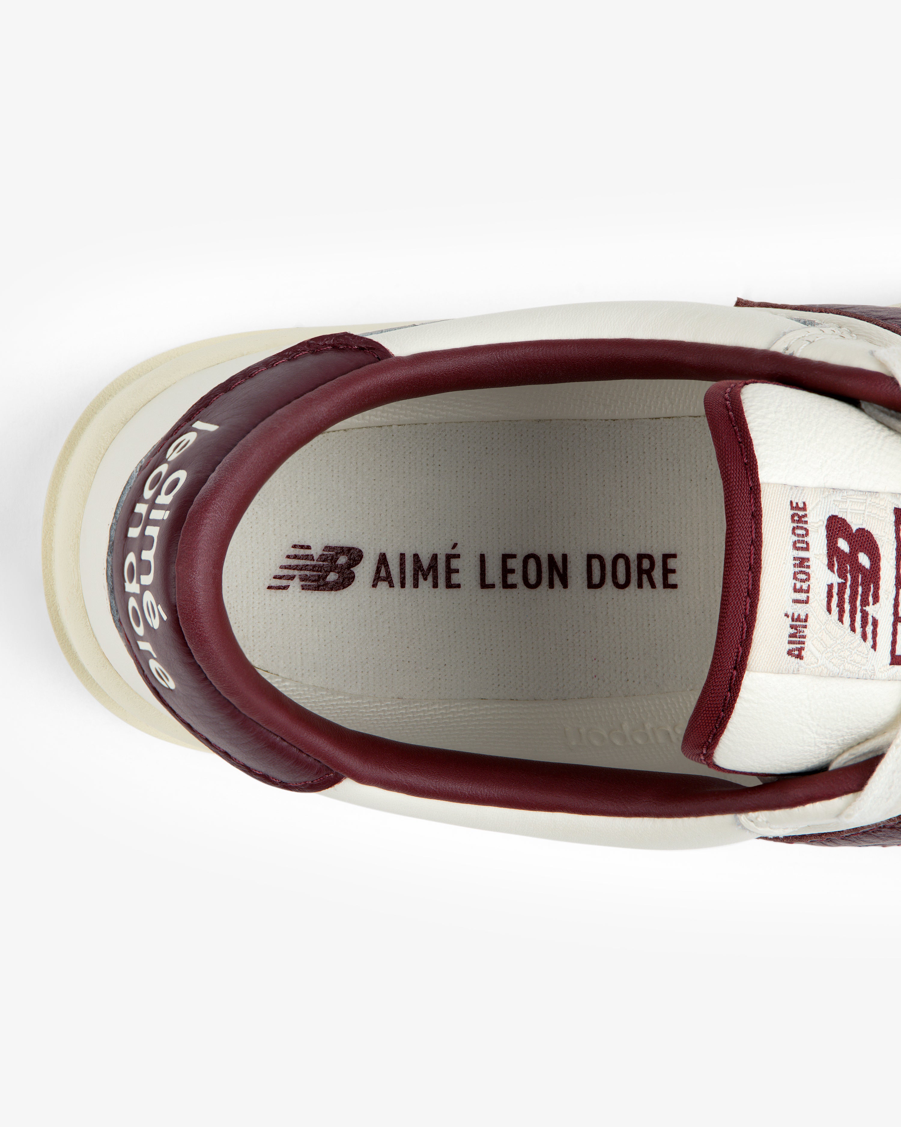 Top-down view of the interior of a cream and maroon ALD / New Balance T500 Tennis Oxfords, showing heel, tongue, and insole.