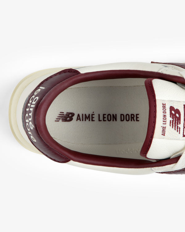 Top-down view of the interior of a cream and maroon ALD / New Balance T500 Tennis Oxfords, showing heel, tongue, and insole.