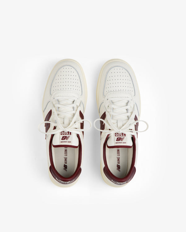 Top-down view of cream-colored ALD / New Balance T500 Tennis Oxfords with burgundy heel collars and logo accents.