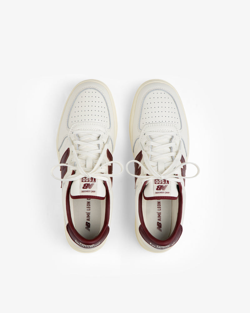 Top-down view of cream-colored ALD / New Balance T500 Tennis Oxfords with burgundy heel collars and logo accents.