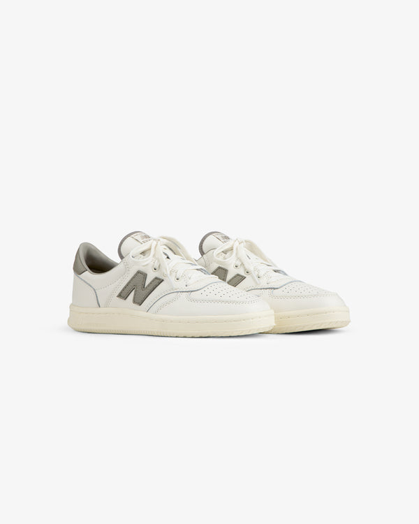 ALD / New Balance T500 Tennis Oxfords: off-white low-top sneakers with grey logo accents and white laces.