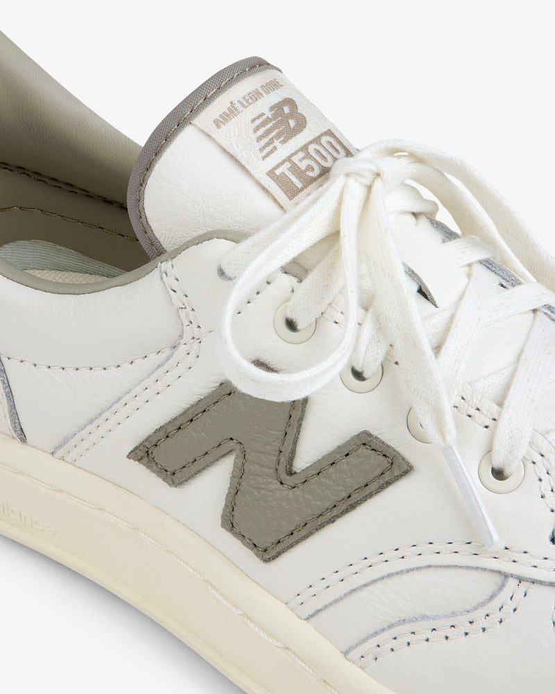 Close-up of a cream-colored ALD / New Balance T500 Tennis Oxford with a grey N logo and matching grey tongue label.