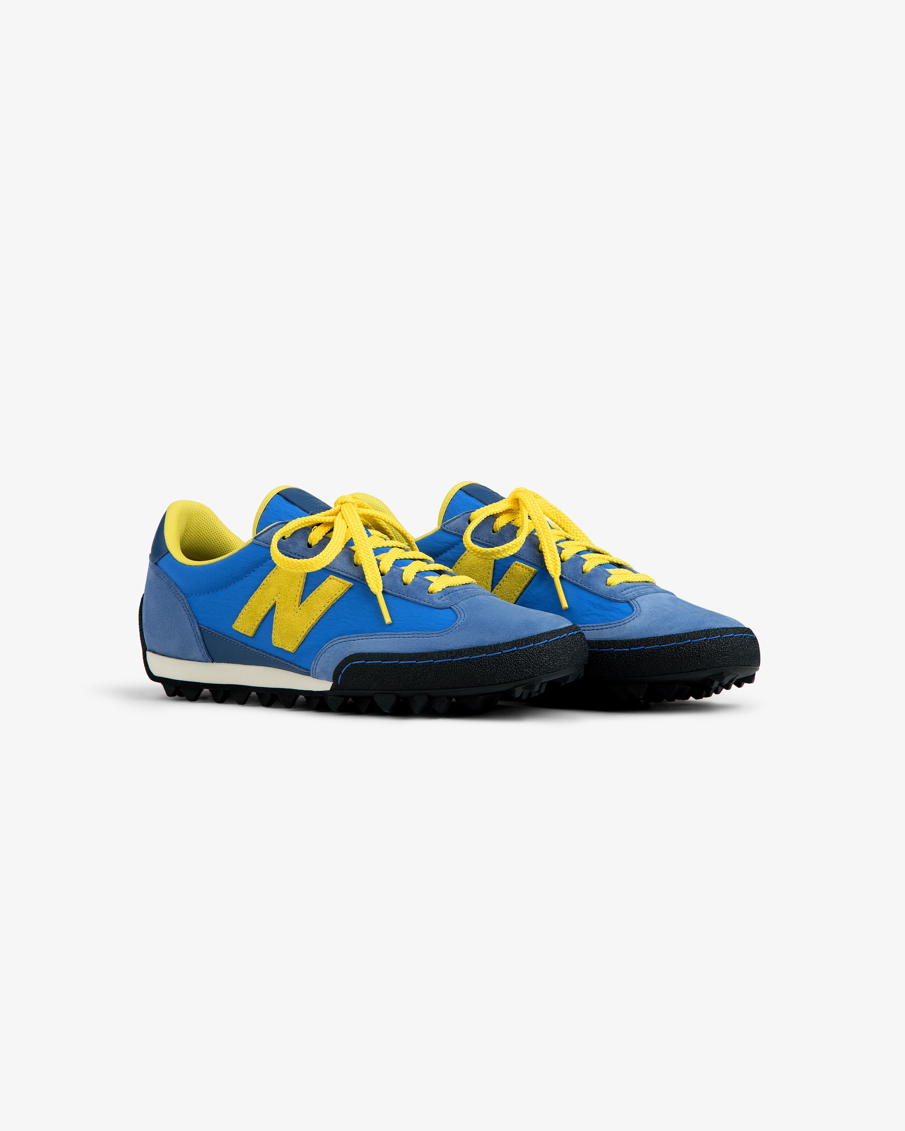 ALD / New Balance Gator low-top sneakers in blue and yellow with yellow laces and a black lugged sole.