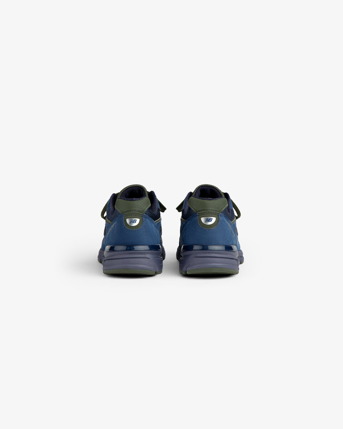New Balance Made in USA 990v4 sneakers in blue and green, viewed from the back against a plain white background.