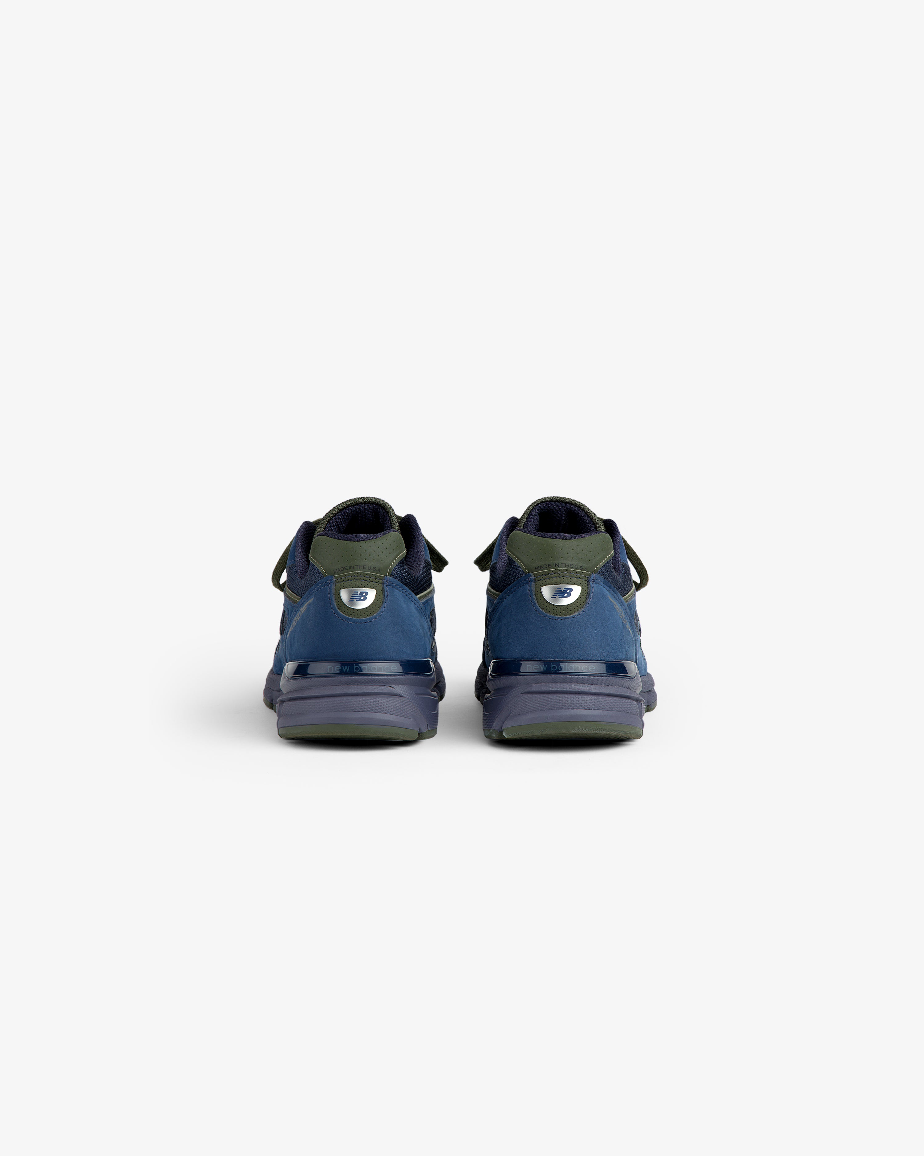New Balance Made in USA 990v4 sneakers in blue and green, viewed from the back against a plain white background.