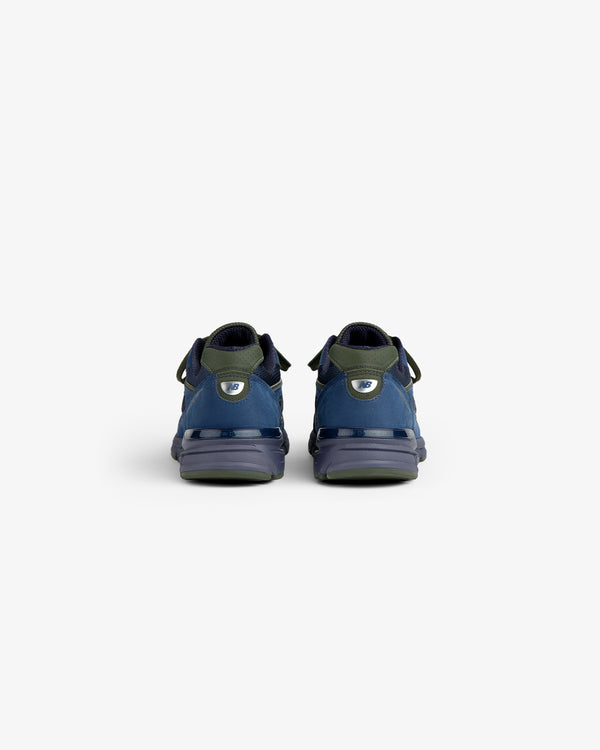 New Balance Made in USA 990v4 sneakers in blue and green, viewed from the back against a plain white background.