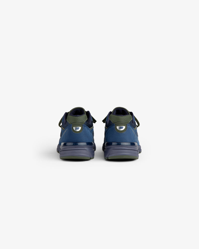New Balance Made in USA 990v4 sneakers in blue and green, viewed from the back against a plain white background.