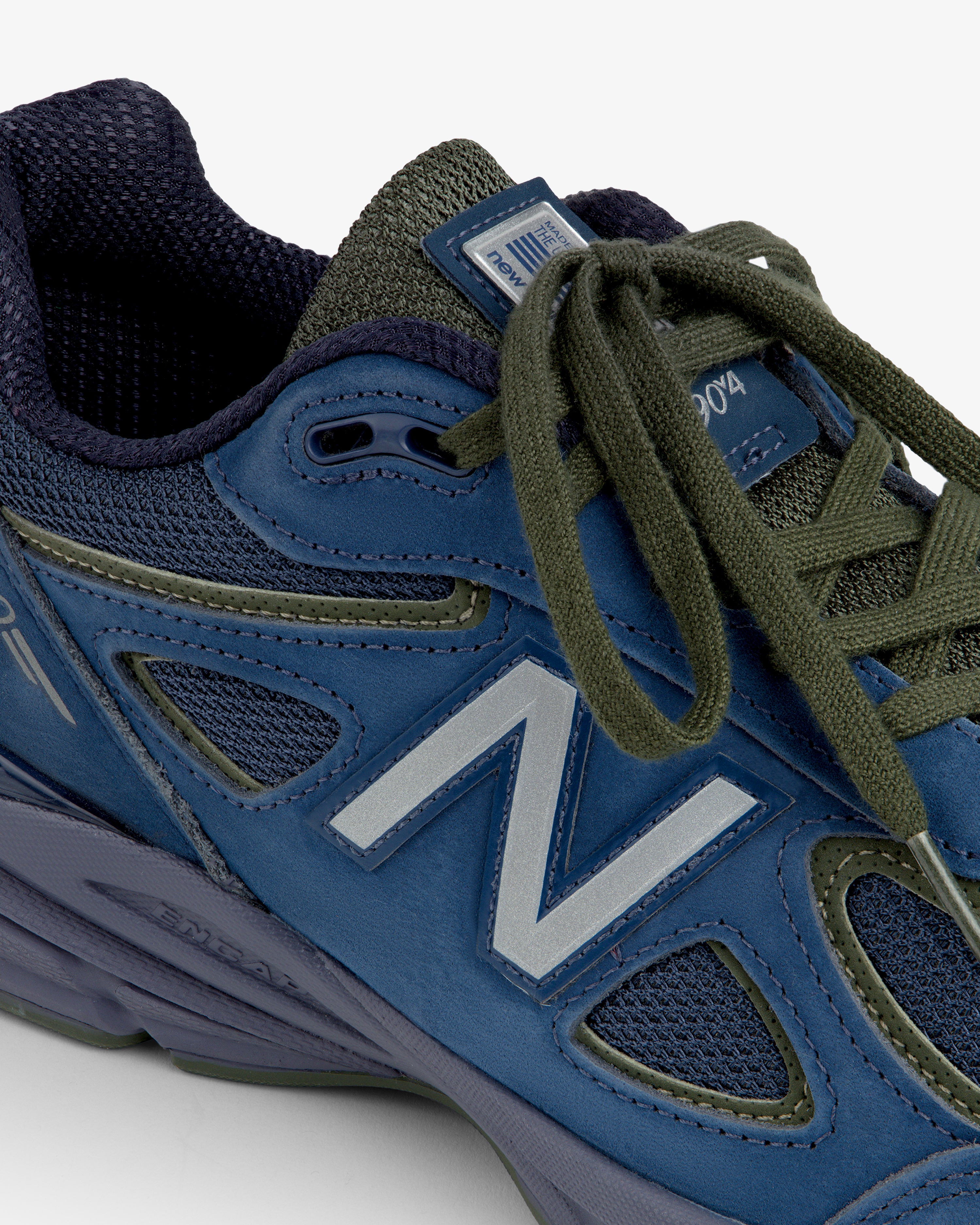 Close-up of a New Balance Made in USA 990v4 in blue and green with green laces and mesh accents.