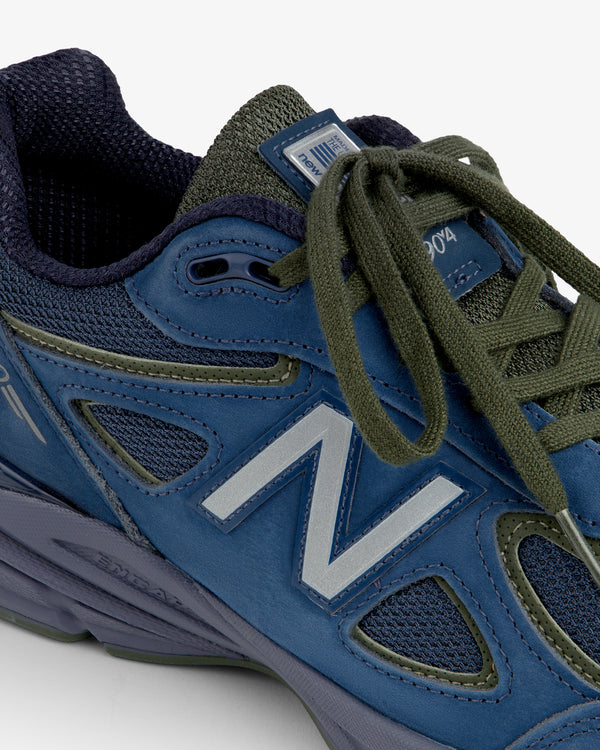 Close-up of a New Balance Made in USA 990v4 in blue and green with green laces and mesh accents.