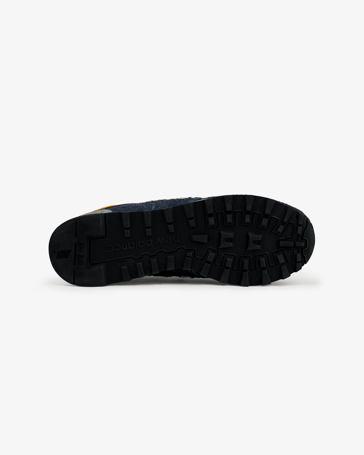 Black rubber sole of ALD / New Balance Made in USA 1300 shoe viewed from bottom, showing tread pattern and logo.