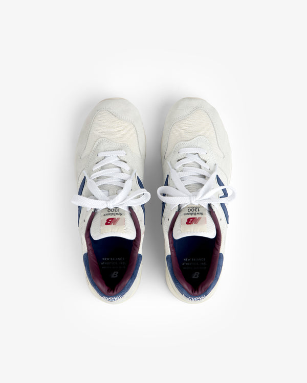 New Balance Made in USA 1300 sneakers in white with blue and maroon accents, top view on a white background.