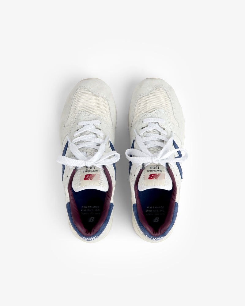 New Balance Made in USA 1300 sneakers in white with blue and maroon accents, top view on a white background.