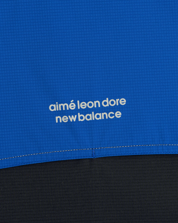 Close-up of blue ALD / New Balance Performance Nylon Jacket with white text above a seam.