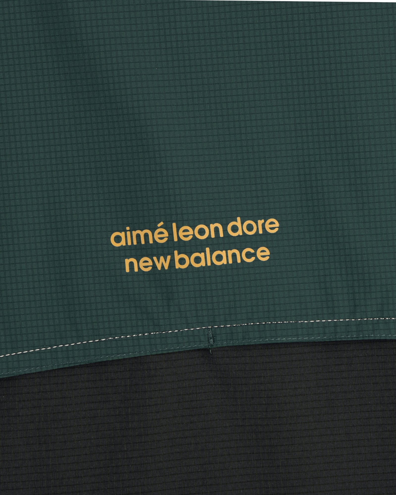Close-up of green and black ALD / New Balance Performance Nylon Jacket with yellow printed text.