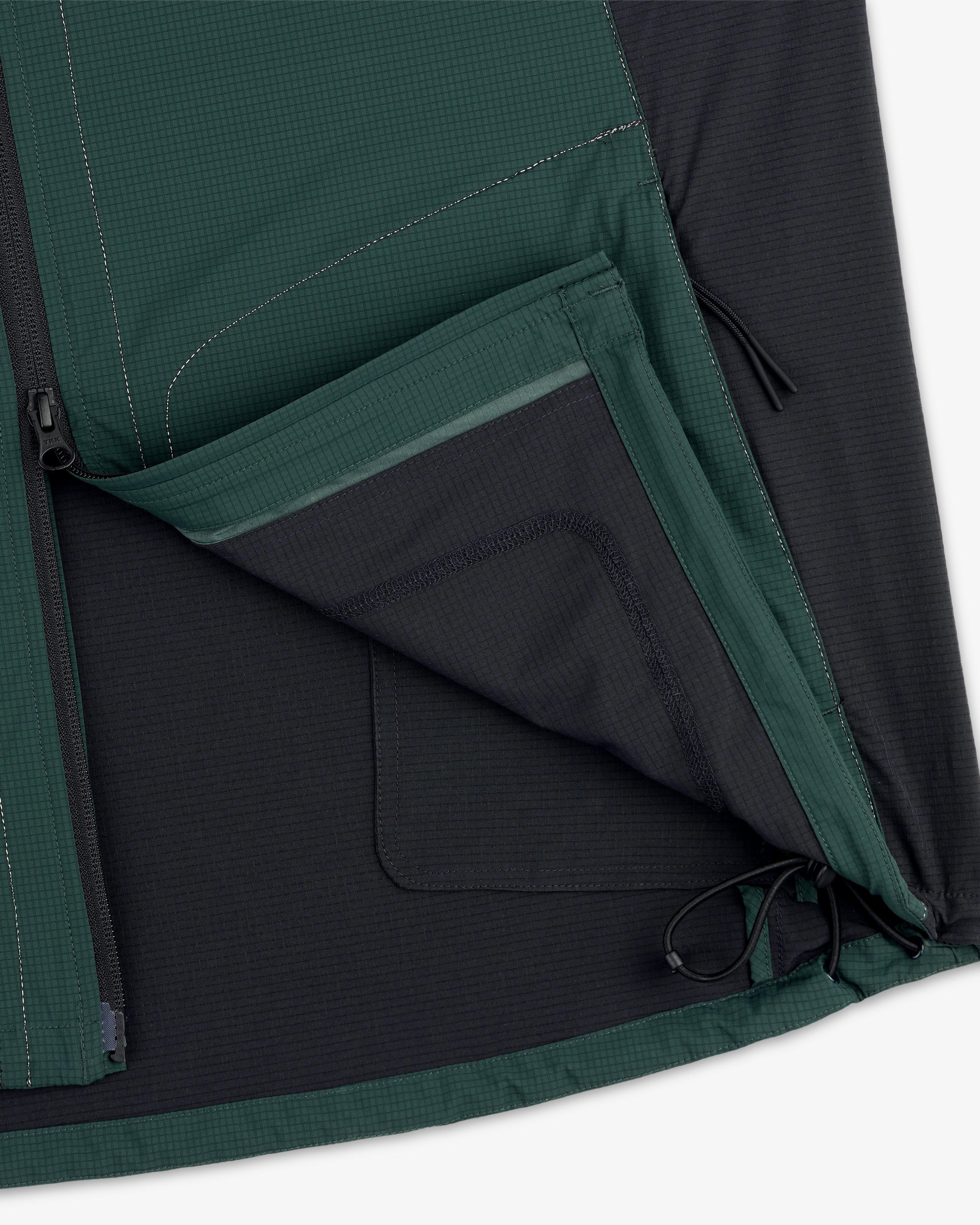 Close-up of the ALD / New Balance Performance Nylon Jacket showing an open zippered pocket and hem drawstring.