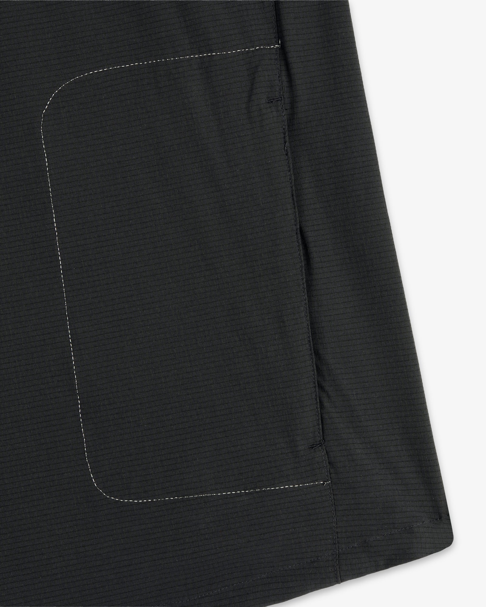 Close-up of the ALD / New Balance Performance Nylon Jacket showing a black fabric, rectangular pocket, and white stitching.