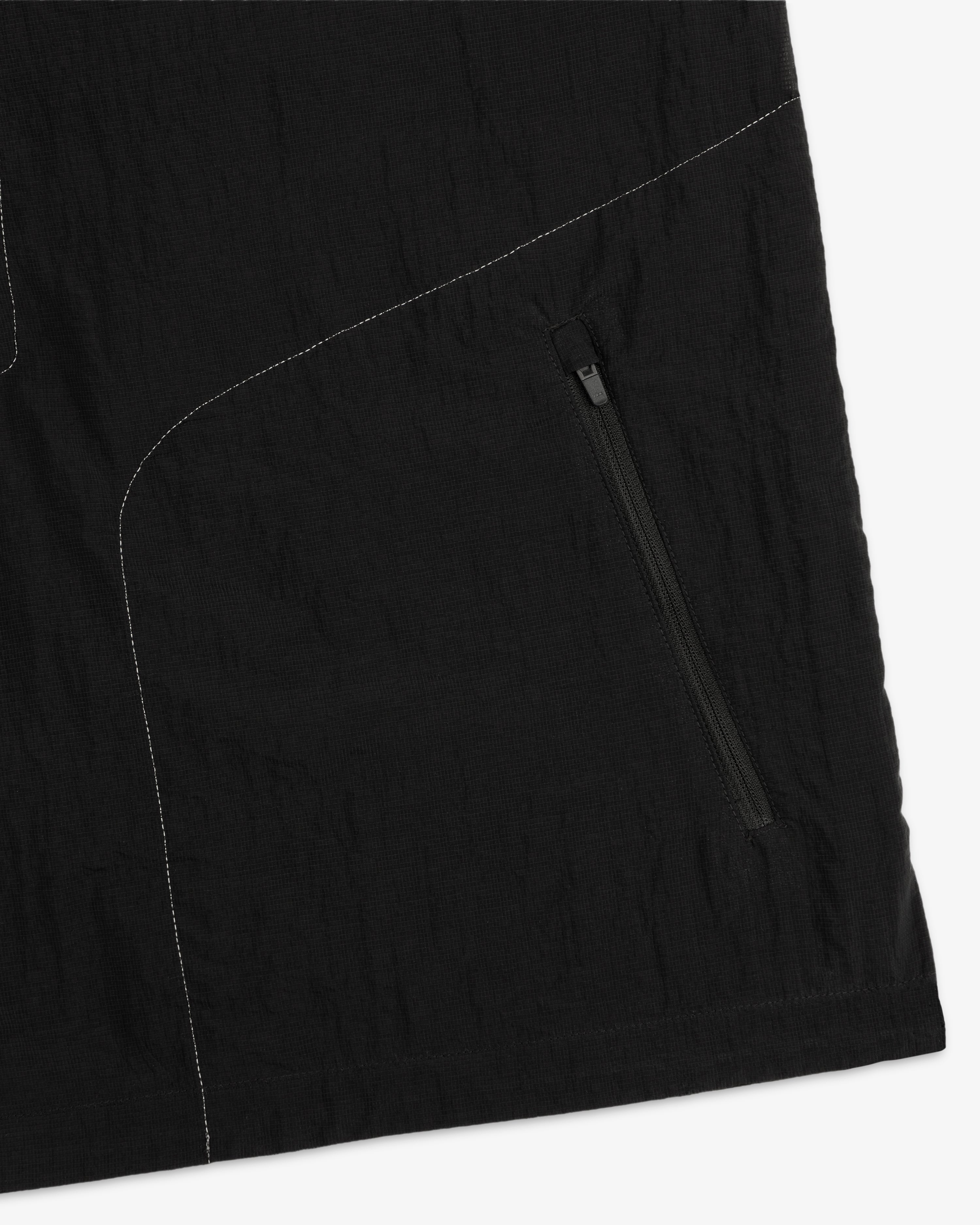 Close-up of ALD / New Balance Breathable Half-Zip Pullover with black fabric, zipper pocket, and white stitching.